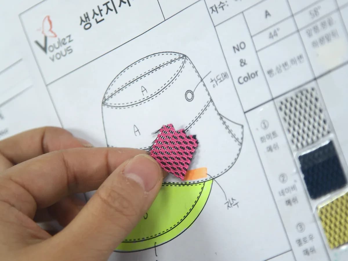 생산지시서에 원단 견본을 대 보며 사양을 정하는 모습